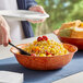 A person holding a bowl of corn salad on a table.