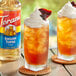A glass of iced tea with whipped cream and Torani English Toffee syrup next to a bottle of Torani English Toffee syrup.