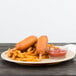 A plate of hot dogs and french fries on a Carlisle tan melamine plate with a bowl of ketchup.