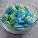 A bowl of Vidal blue and green gummy candies on a table.