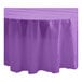 A purple Table Mate plastic round tablecloth with a ruffled edge on a table.