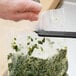 A person using a Tangibles Pouchmate to cut green herbs in a plastic bag.