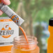A hand pouring Gatorade Zero Sugar Orange powder into a jar.