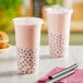 Two Choice clear plastic cups with pink liquid and black straws.