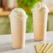 Two Choice clear PET plastic cups with milkshakes and whipped cream on top with straws.