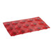 A red silicone round baking sheet with 15 micro-perforated compartments.
