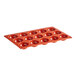 A red Pavoni round silicone baking mold with 15 compartments.