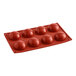A red Pavoni silicone baking mold with round balls on a white surface.