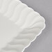 A Fineline Flairware ivory plastic snack tray with a wavy edge.