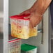A person holding a Cambro CamSquares container of food with fruit in it.