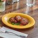 An Acopa yellow melamine platter with food on it.
