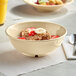 A tan Acopa Foundations melamine bowl filled with oatmeal and fruit with a spoon.