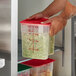 A person holding a Cambro CamSquares food storage container filled with food.