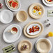 A table set with Acopa Foundations white melamine plates, bowls, and cups of food.