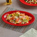 A red Acopa Foundations melamine platter of nachos with cheese and peppers.