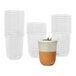 A Tossware Natural rounded bottom plastic cup with a brown liquid next to a stack of clear plastic cups.