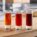 A group of glasses with different colored liquid on a table in a brewery tasting room.