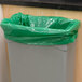 A garbage can with a green Low Density Trash Can Liner over it.
