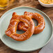 Two Eastern Standard Provisions soft pretzels on a plate with a bowl of beer.