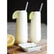 Two Tossware plastic champagne flutes filled with lemonade and straws with lime slices.