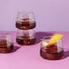 Tossware POP 12 oz. plastic rocks glasses filled with brown liquid, ice, and lemon slices.