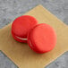 Two red Coco Bakery red velvet macarons on a brown paper.
