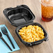 A Genpak black plastic hinged container with macaroni and cheese inside.