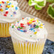 A cupcake with white frosting and Supernatural Rainbow Starfetti stars on top.
