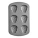 A Wilton baking pan with six mini skull-shaped cake compartments.
