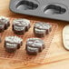 A cooling rack with chocolate mini skull cakes on it.