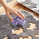 A person's hand using a Wilton bat cookie cutter to cut out dough.