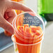 A hand holding a World Centric clear plastic container of carrots.