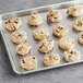 A tray of Otis Spunkmeyer Milk Chocolate Chunk cookies on a gray surface.