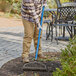 A person using a Seymour rake with a blue fiberglass handle.