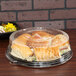 A Sabert clear plastic container with sandwiches and other food with a high dome lid.