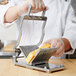 A person using a Vollrath CubeKing cheese slicer to slice cheese.