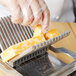 A person slicing cheese with a Vollrath CubeKing cheese slicer.