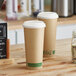 Two EcoChoice Kraft paper cups with white PLA lids on a wooden table.