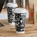 Two Choice double wall paper hot cups with black and white coffee break designs and lids.
