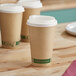 Three EcoChoice Kraft paper cups with PLA lids on a table.