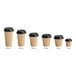 A row of Choice 4 oz. Double Wall Ripple Kraft Paper hot cups with black lids.