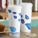 Two EcoChoice paper hot cups with blue leaf print on them.
