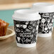 Two Choice double wall paper coffee cups and a muffin on a table.