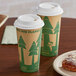 Two EcoChoice paper coffee cups with a tree print on the table with a plate of pastries.