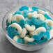 A bowl of Albanese Blue Raspberry Gummi Rings and blue and white gummy candy.
