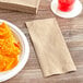 A plate of chips next to a Tork kraft dinner napkin on a table.