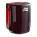 A red and black Tork Maxi center pull paper towel dispenser.