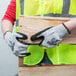 A person wearing Cordova Commander cut-resistant gloves with black foam nitrile palm coating holding a piece of wood.