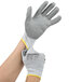 A pair of extra small Cordova gray cut-resistant gloves with gray palms being put on.