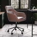 A Martha Stewart Rayana saddle brown faux leather office chair with oil-rubbed bronze finish and wheels in a white room with a plant.